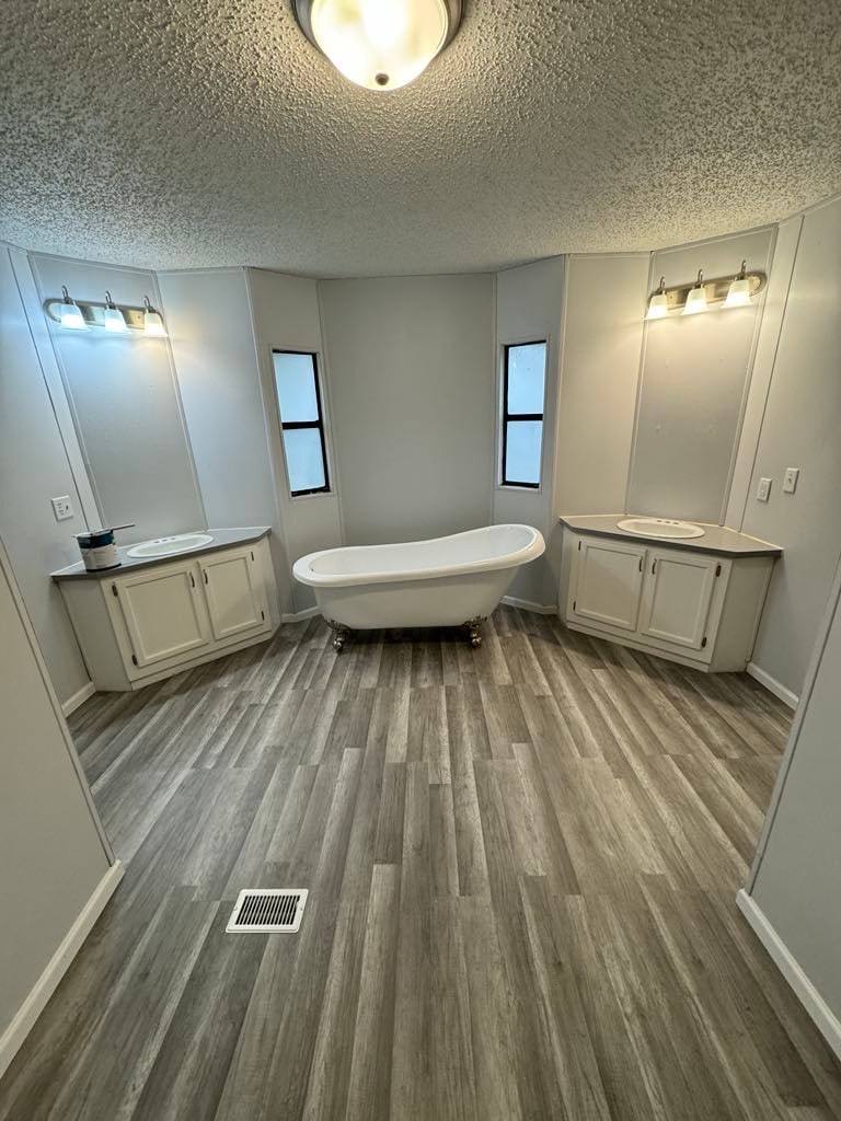 Bathroom with a clawfoot tub set between two white vanities under vanity lights
