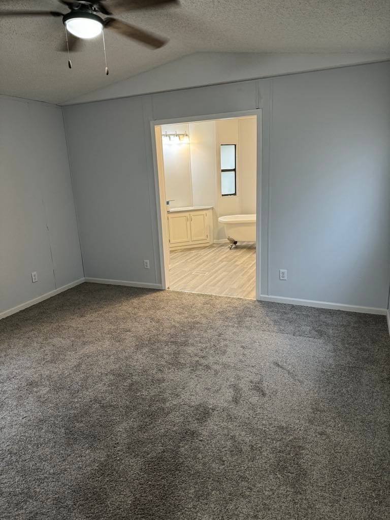 Carpeted bedroom with a ceiling fan and a doorway into its own bathroom