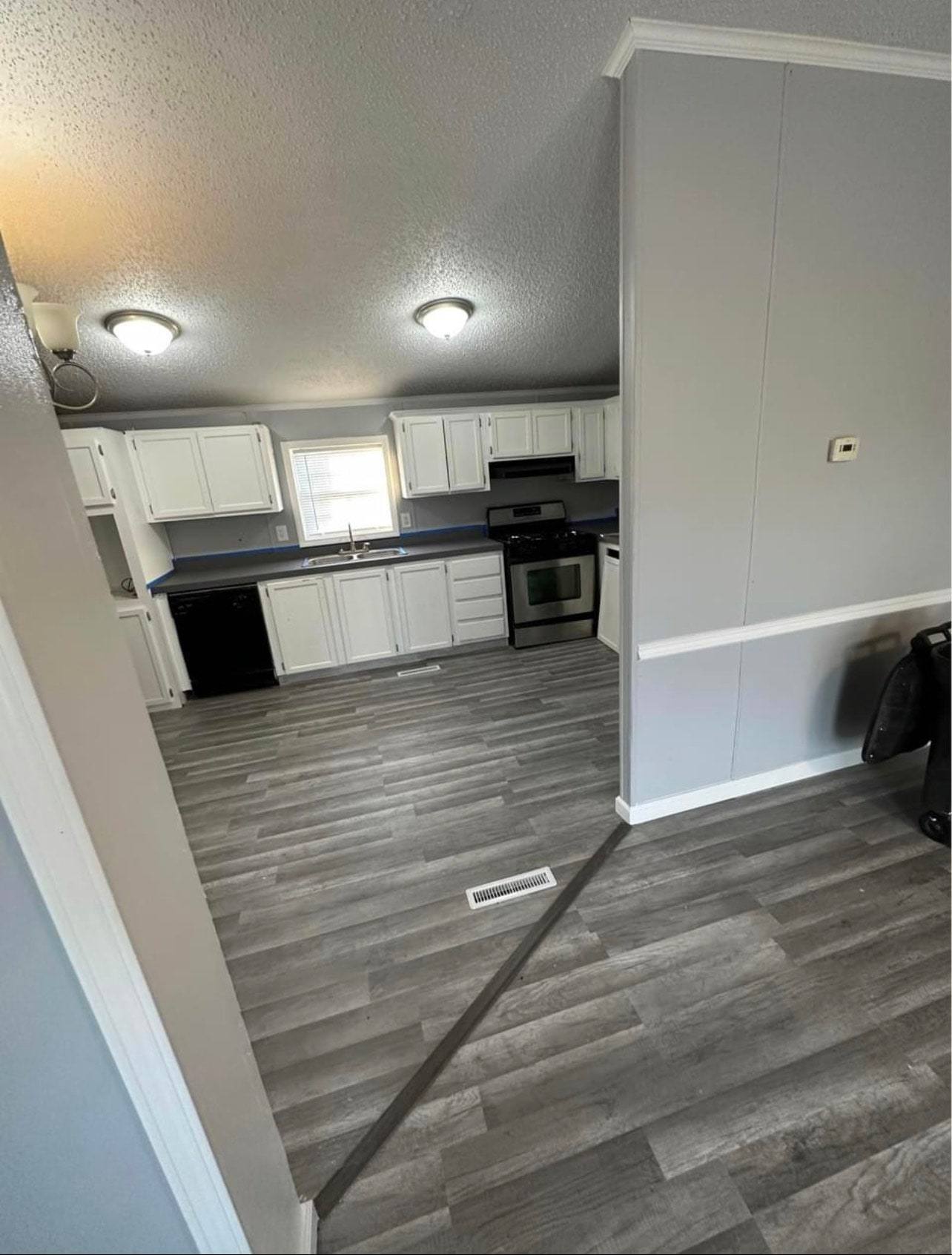 Kitchen with white cabinets, dark countertops, a stainless range and gray plank flooring